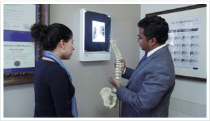 neurosurgeon holding spine and explaining to woman